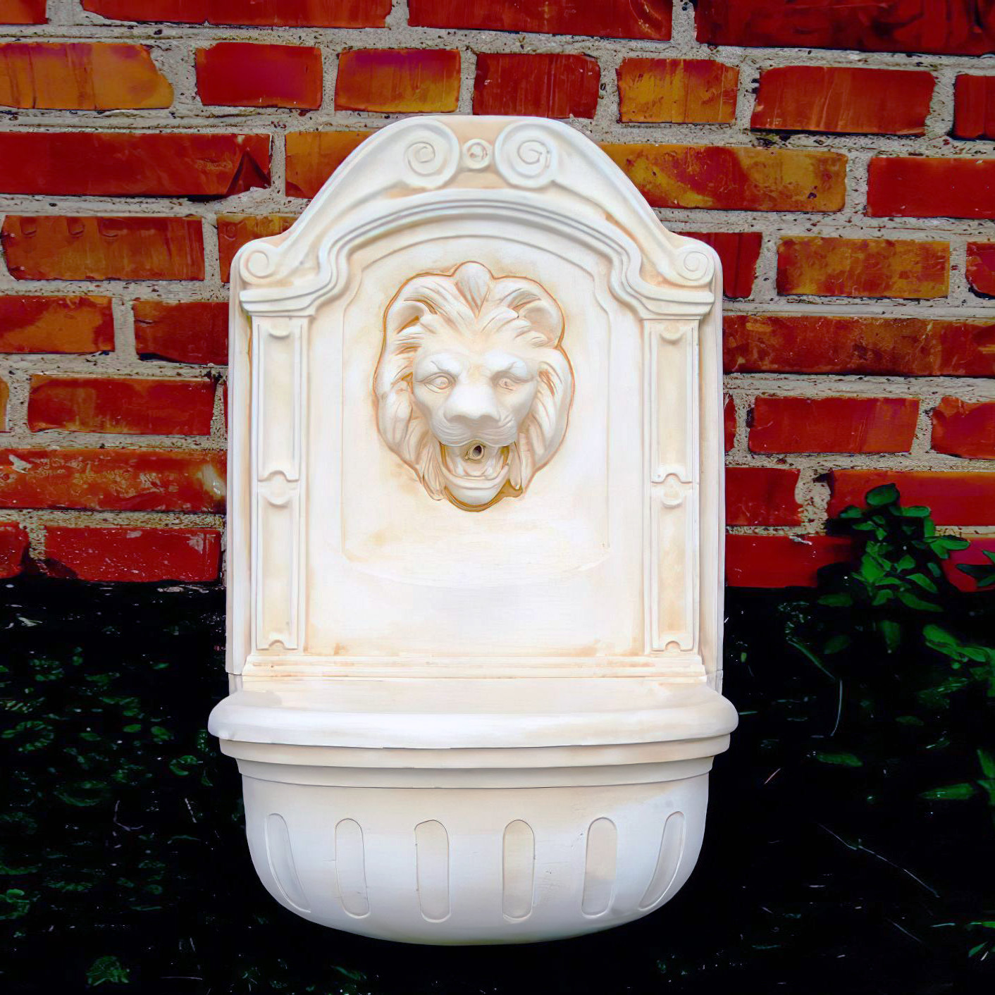 Elegante fontana da parete bianca con testa di leone davanti a un muro di mattoni rossi