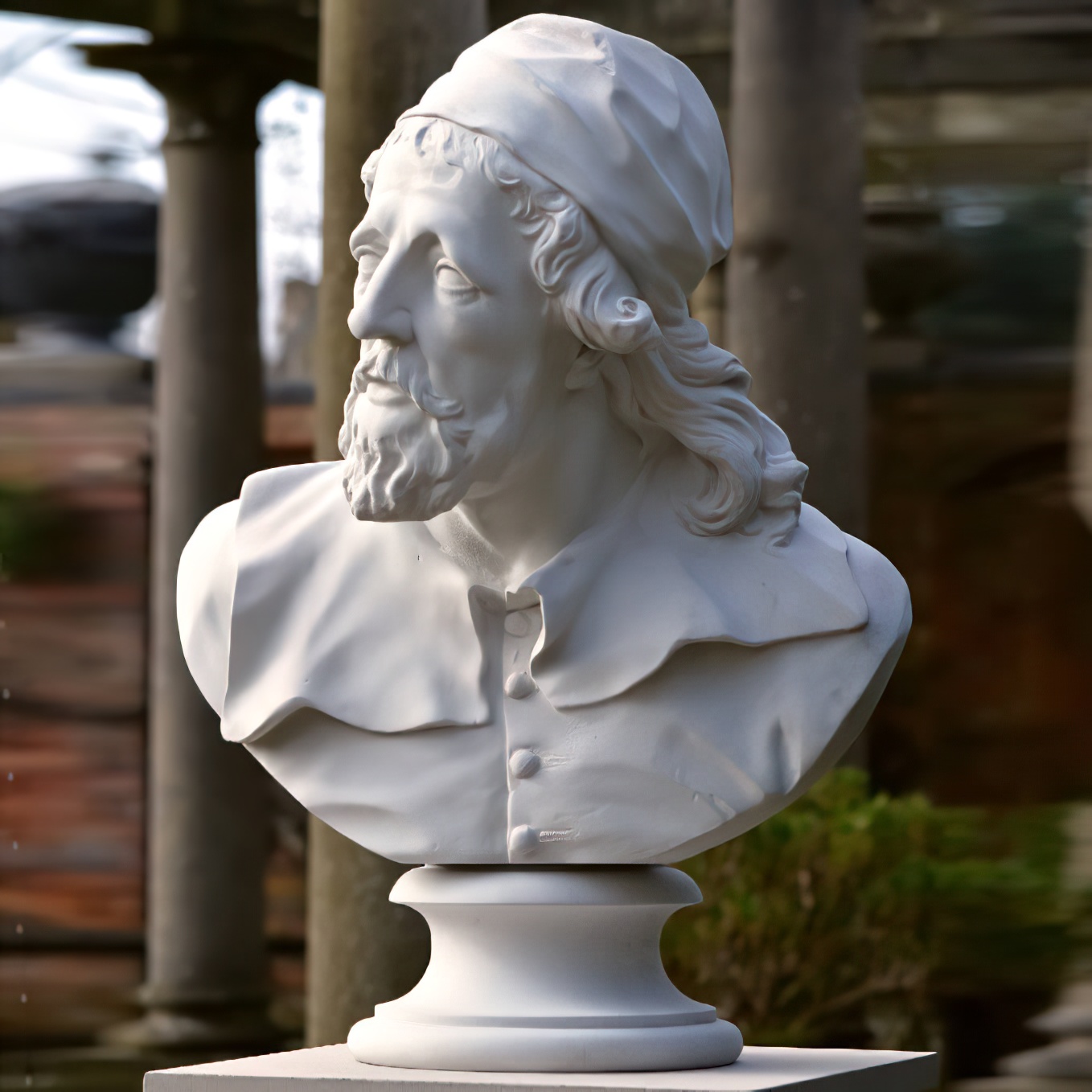 Sculpture de buste en pierre blanche d'un homme barbu portant un bonnet dans un jardin