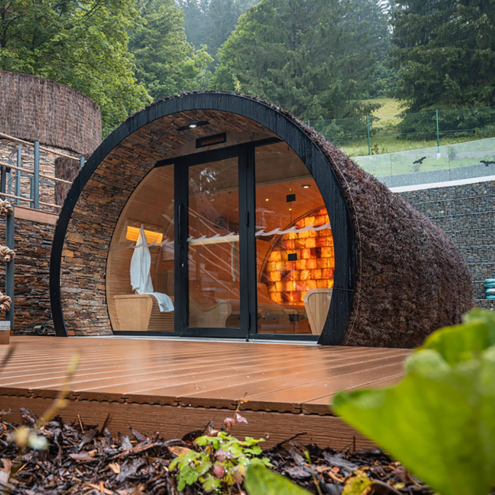Modernes rundes Gartenhaus aus Holz in einem grünen Garten mit Blick auf Berge