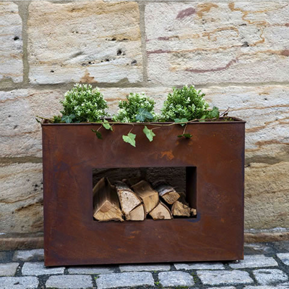 Decorazione da giardino arrugginita con tre piante verdi davanti a un muro di pietra