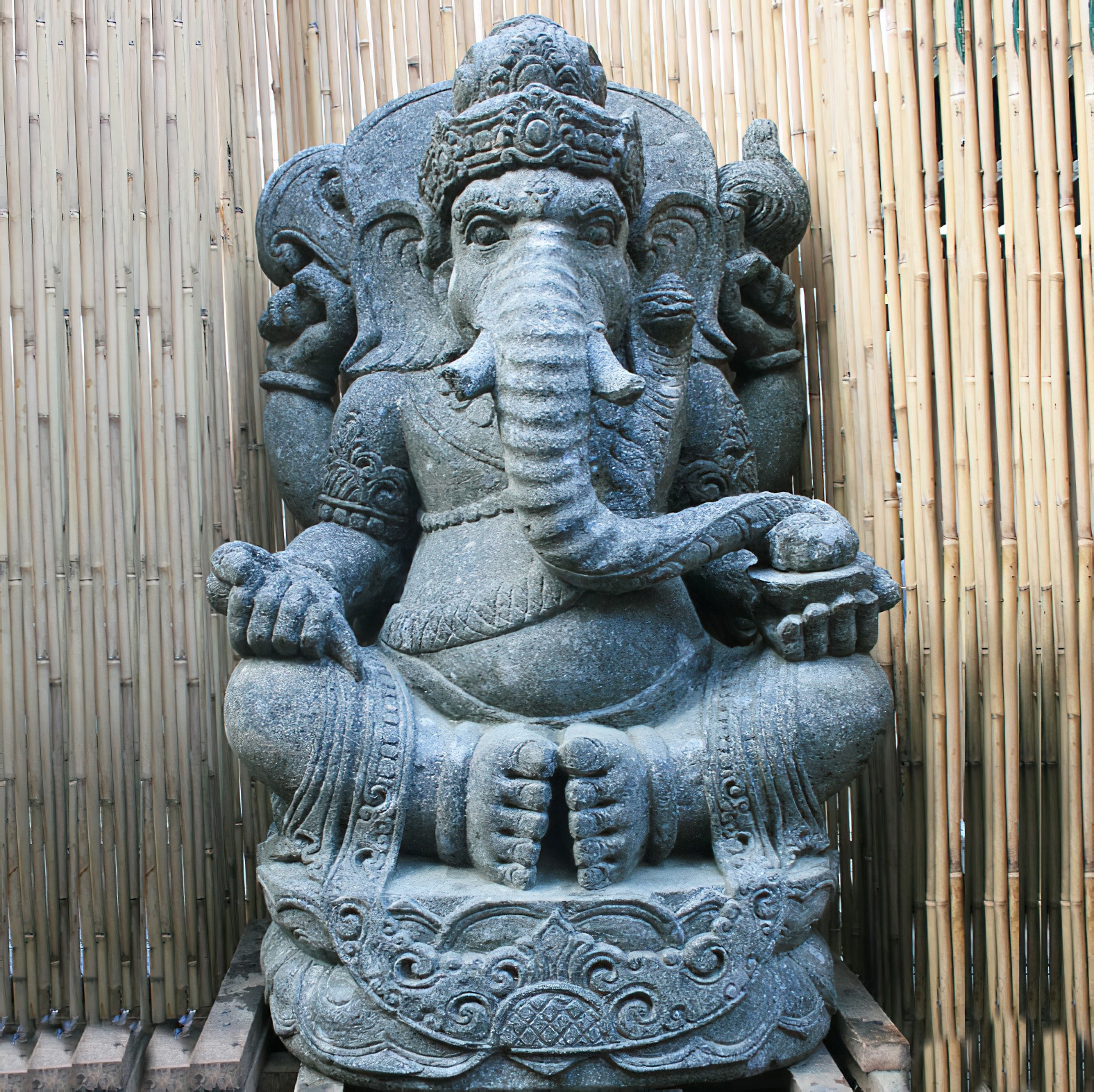 Decorazione da giardino: statua di pietra del dio indù Ganesh davanti a una parete di bambù