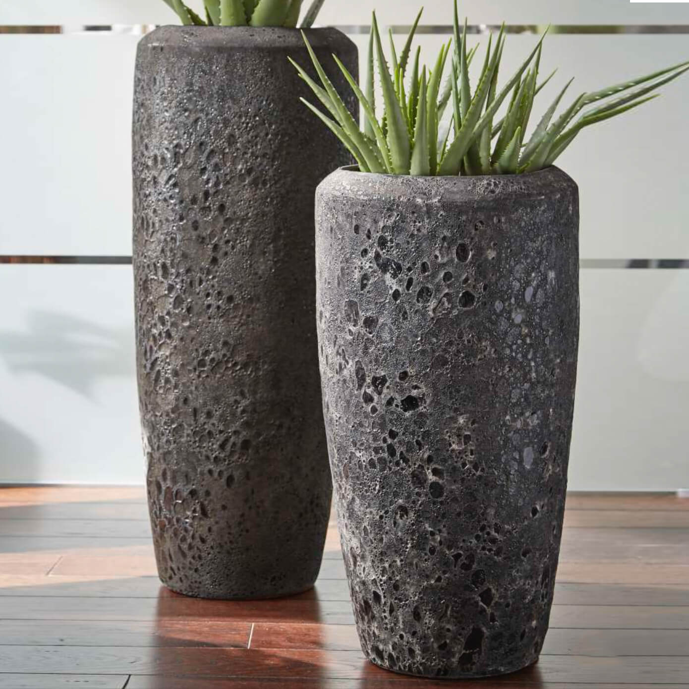 Deux vases en pierre noire élégants avec des plantes vertes dans un cadre de jardin chic