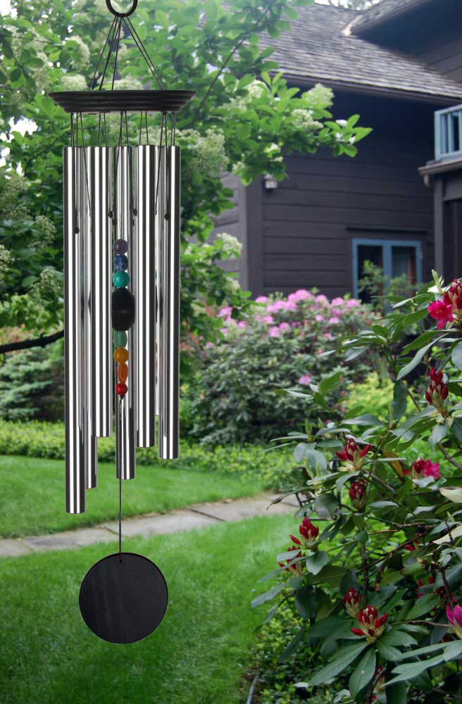 Carillon en métal avec boules colorées suspendu dans un jardin fleuri