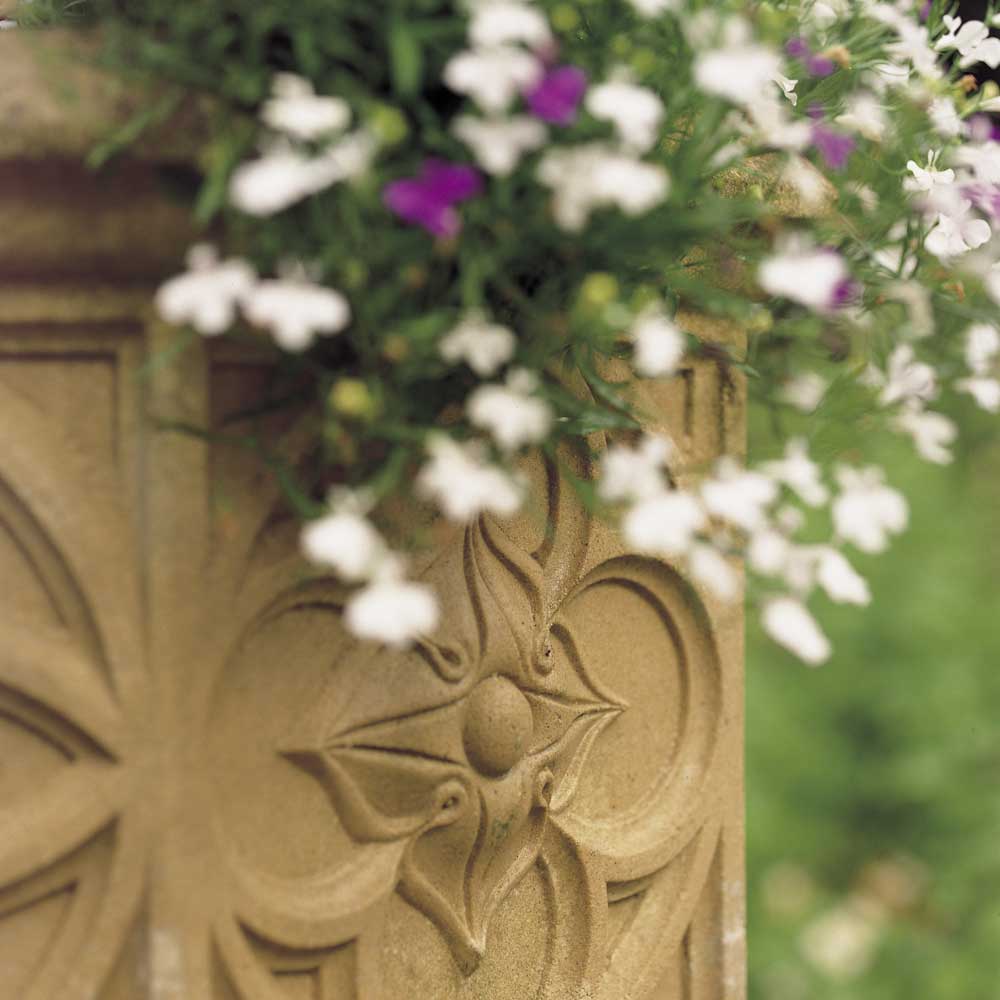 Nahaufnahme eines steinernen Blumentopfes mit Blumen in einem Garten
