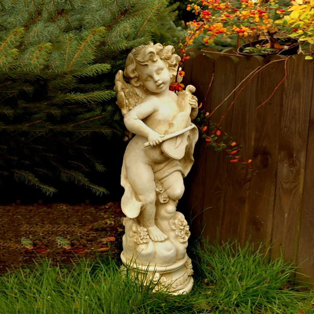 Statua bianca di un angelo con violino in un giardino verde