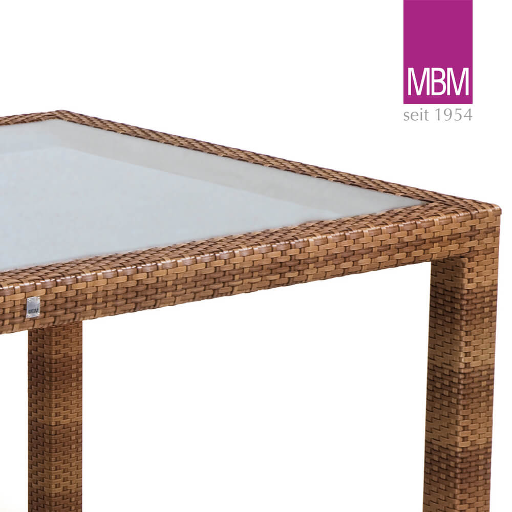 Gros plan sur une table de jardin en osier marron avec plateau en verre