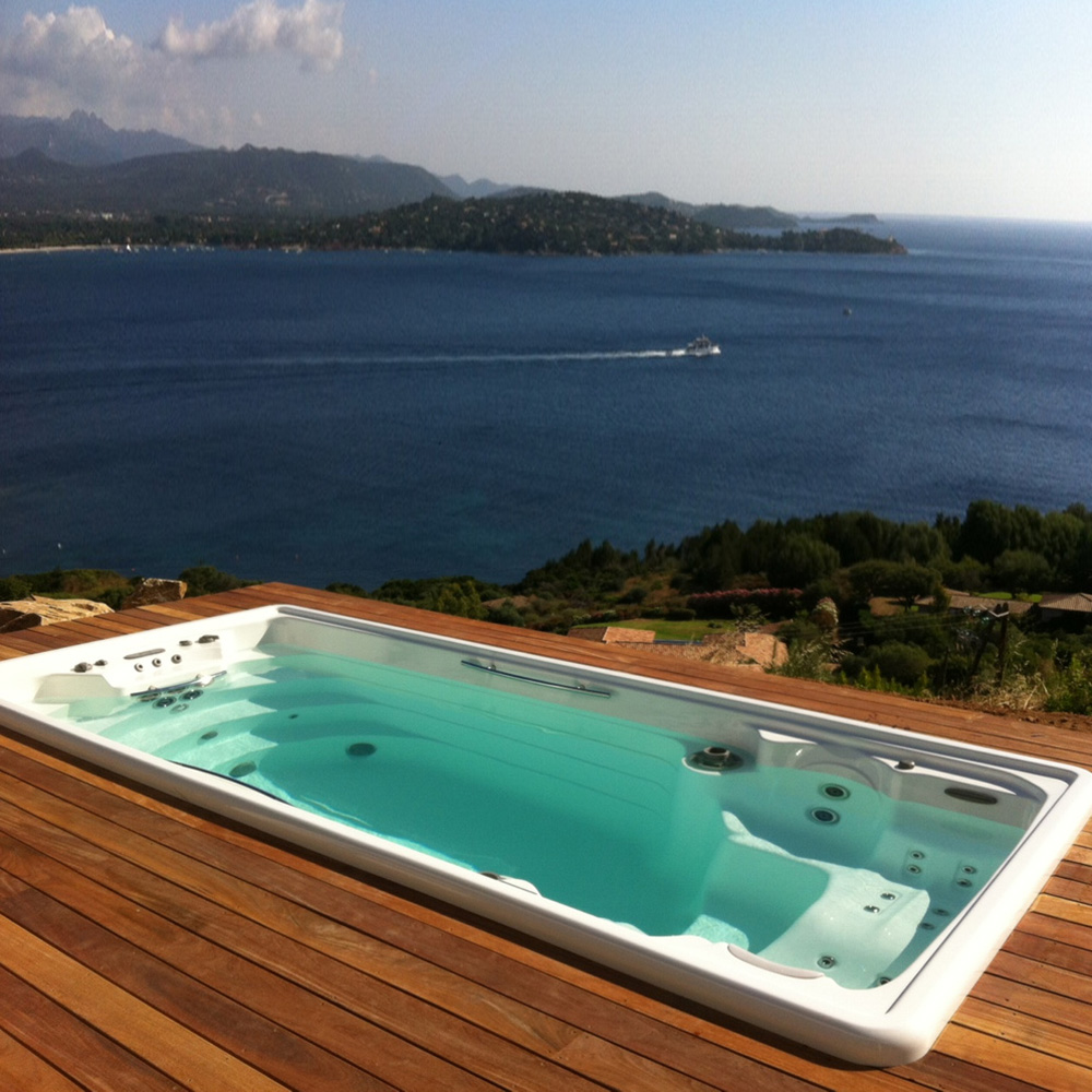 Spa moderne sur une terrasse en bois avec vue sur la mer et le paysage côtier vallonné