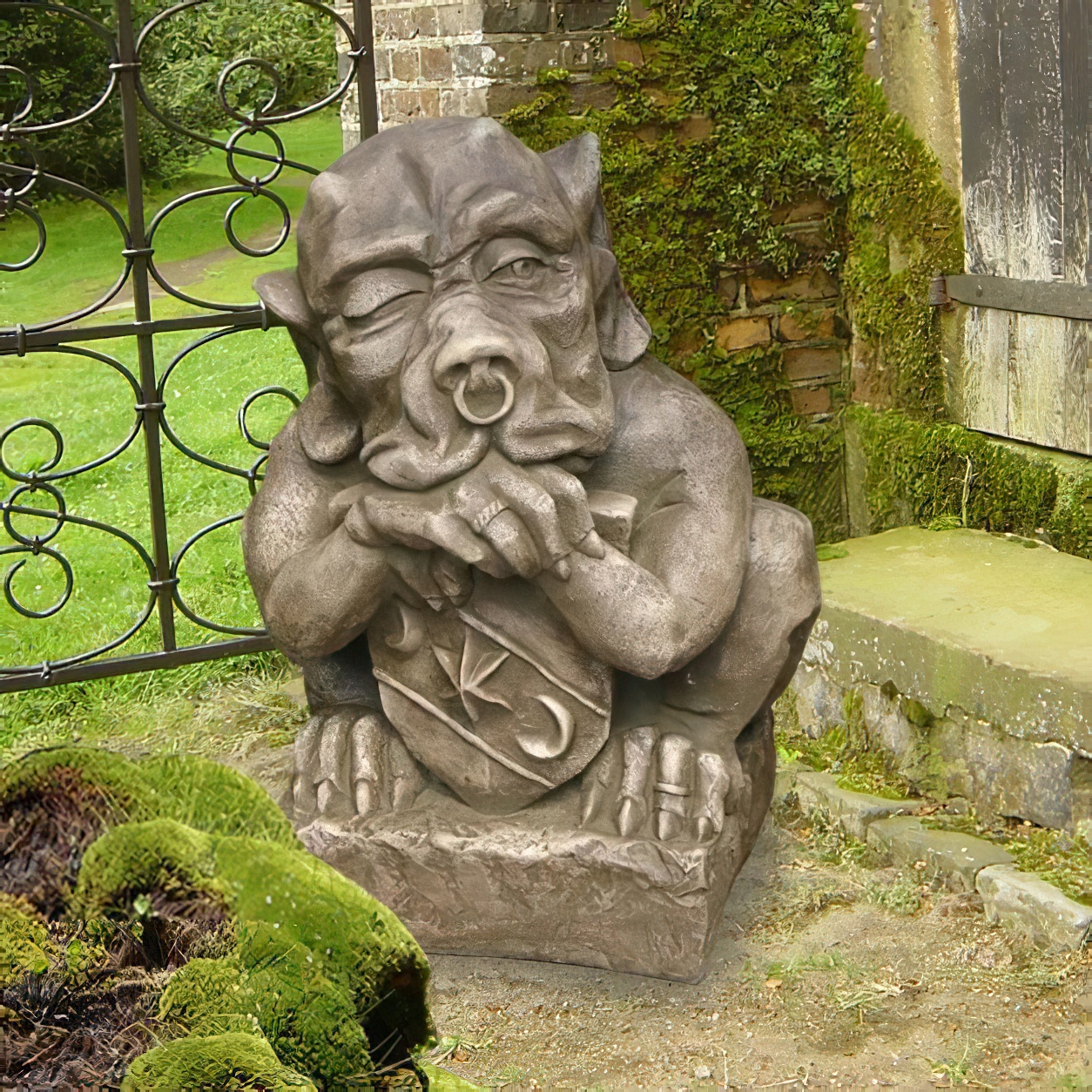 Große steinerne Gargoyle-Gartenskulptur neben einem alten Tor und Moosbewuchs