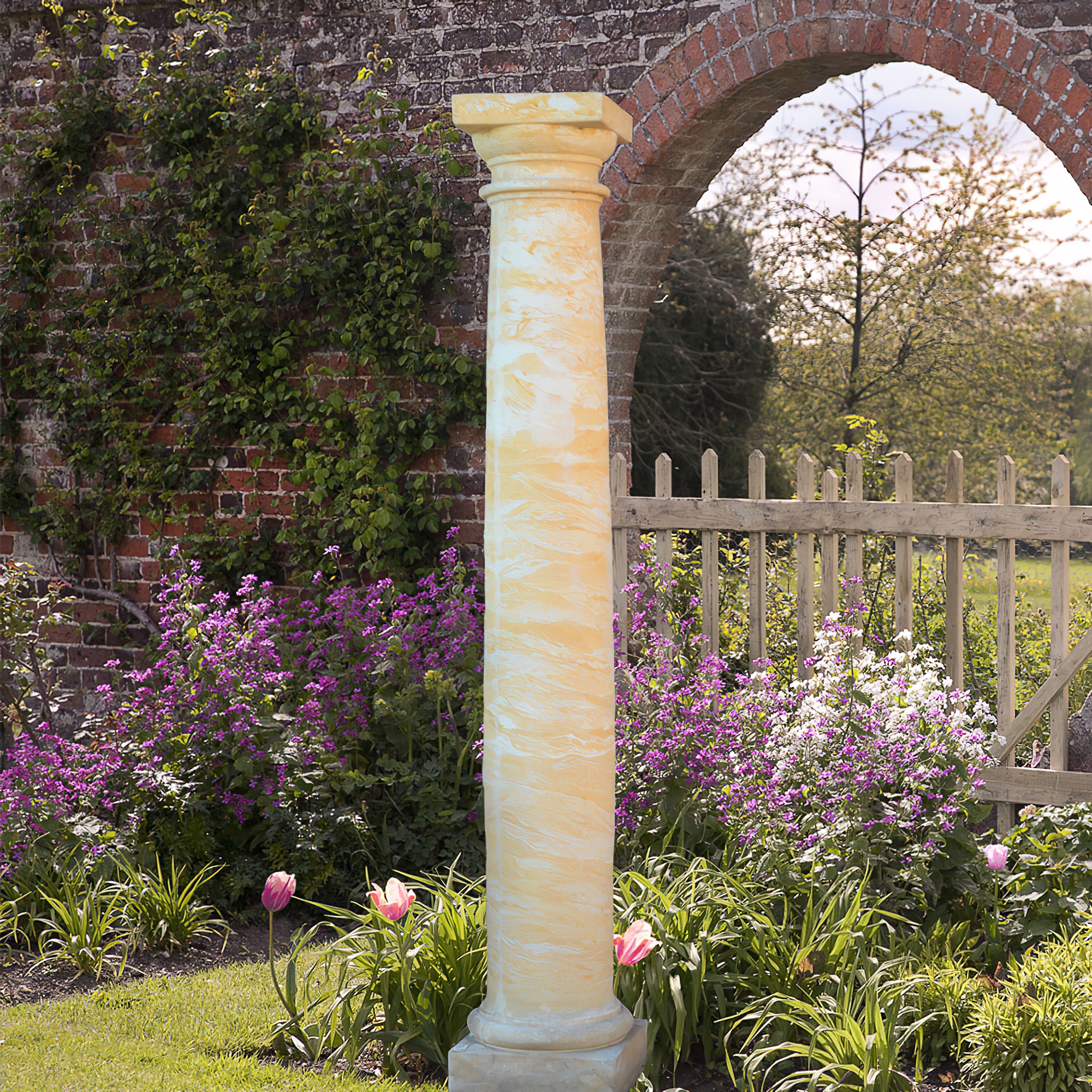 Haute colonne en marbre dans un jardin fleuri avec un mur en pierre en arrière-plan