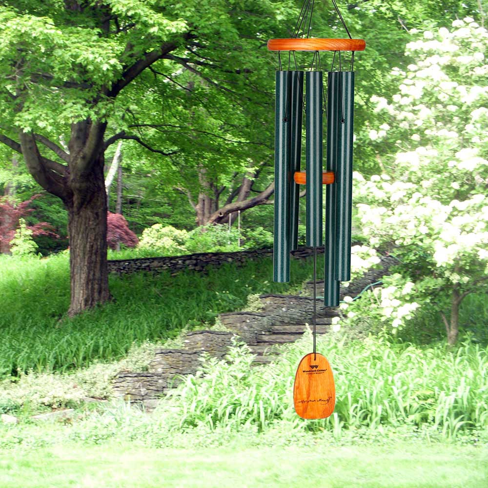 Carillon éolien en métal et bois dans un jardin verdoyant ensoleillé