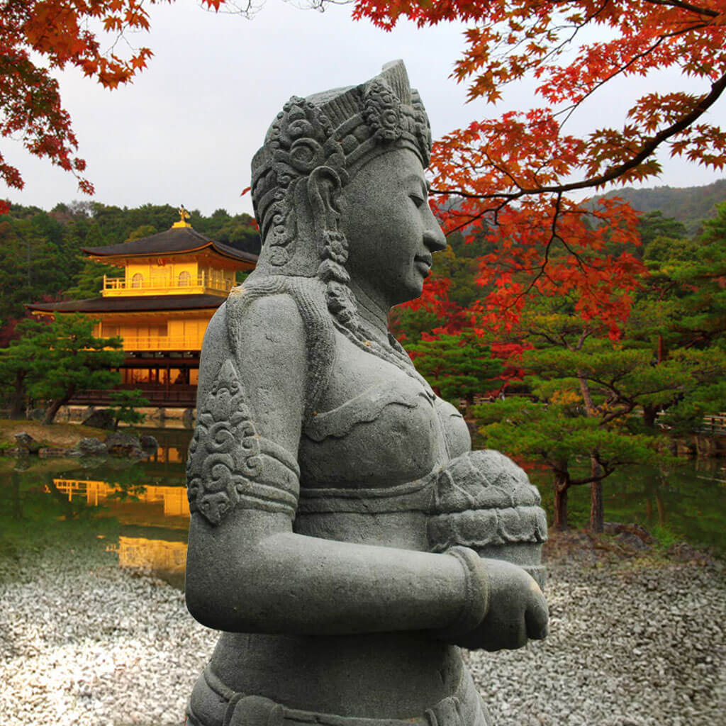 Gros plan d'une sculpture en pierre avec des feuilles rouges d'automne et une maison de jardin en arrière-plan