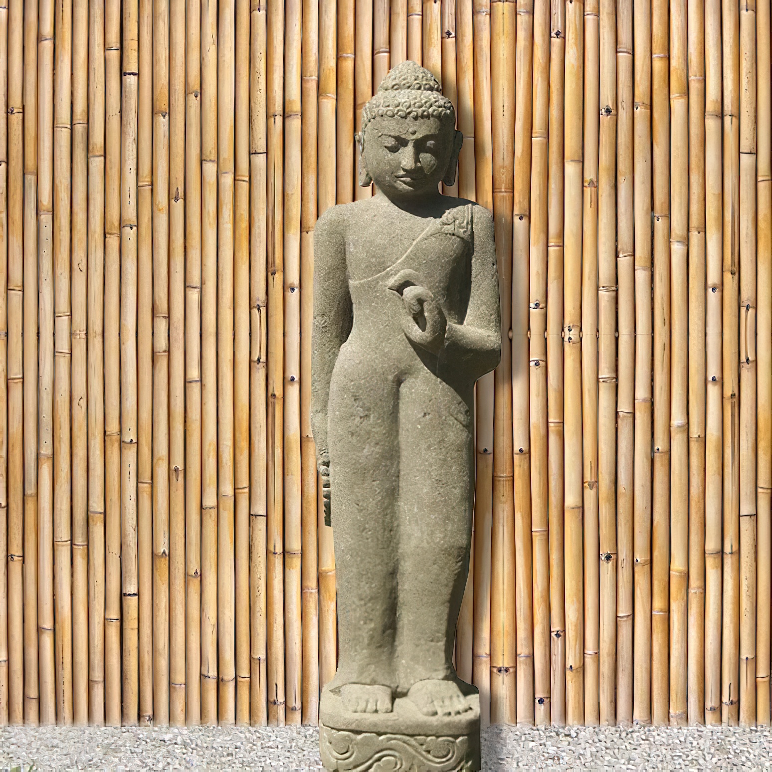 Buddha da giardino in pietra davanti a una parete di canne di bambù disposte verticalmente