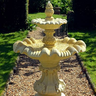 Fontaine de jardin décorative à deux niveaux en pierre dans un jardin ensoleillé