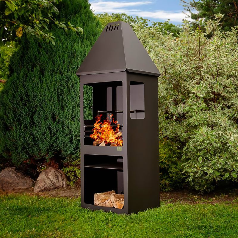 Barbecue da giardino nero con fuoco acceso in un giardino verde
