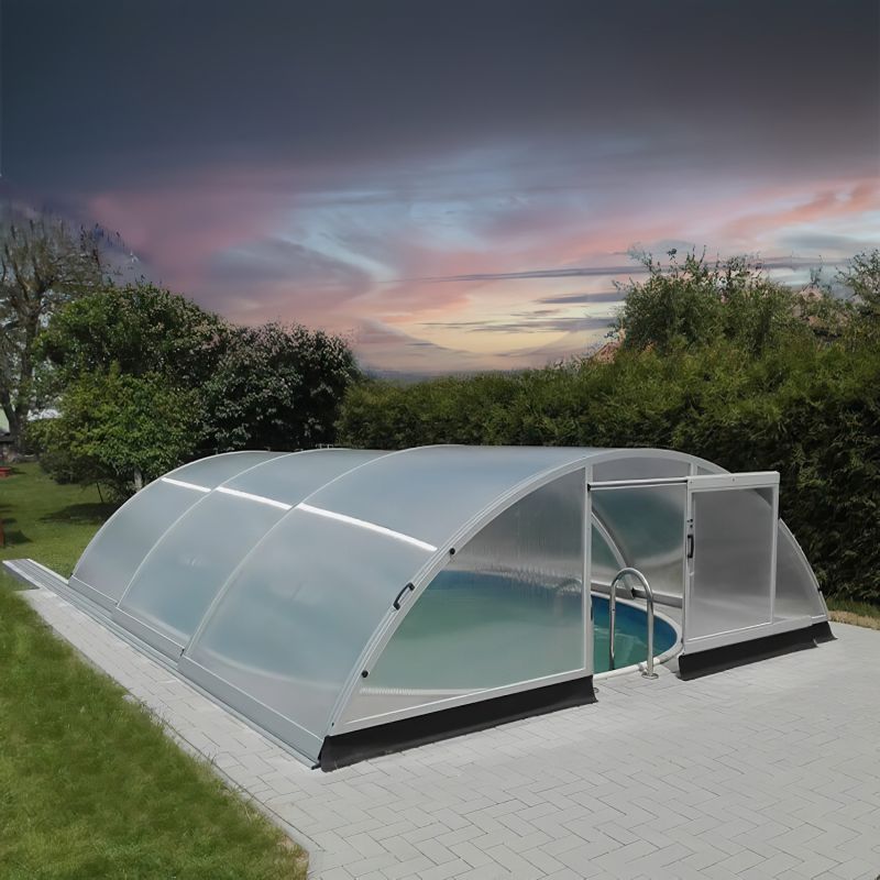 Abri de piscine transparent et cintré sur une nouvelle dalle dans le jardin