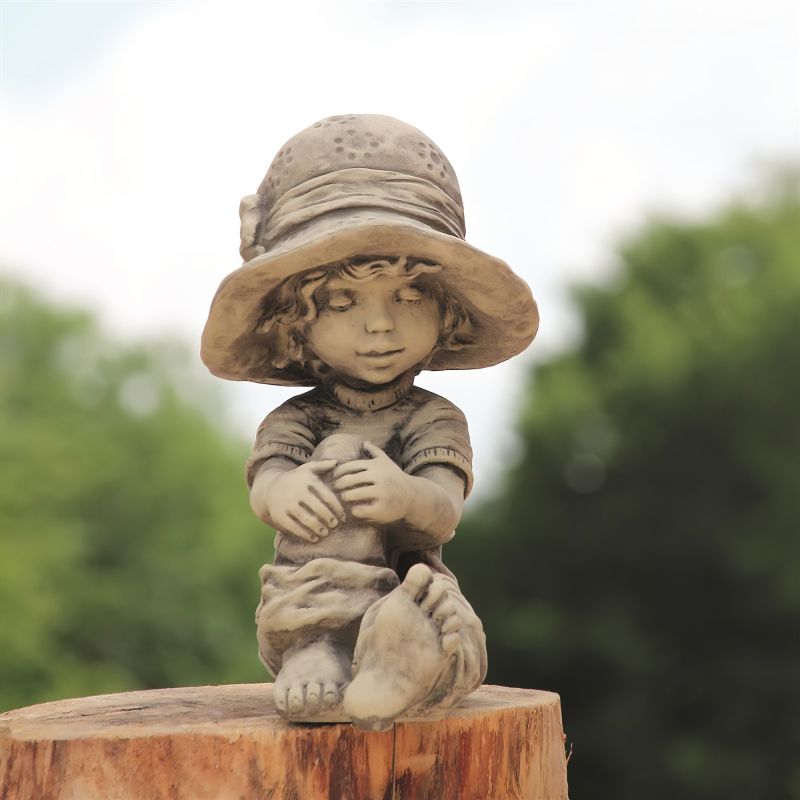 Scultura decorativa da giardino in ceramica di un bambino seduto su un ceppo di legno