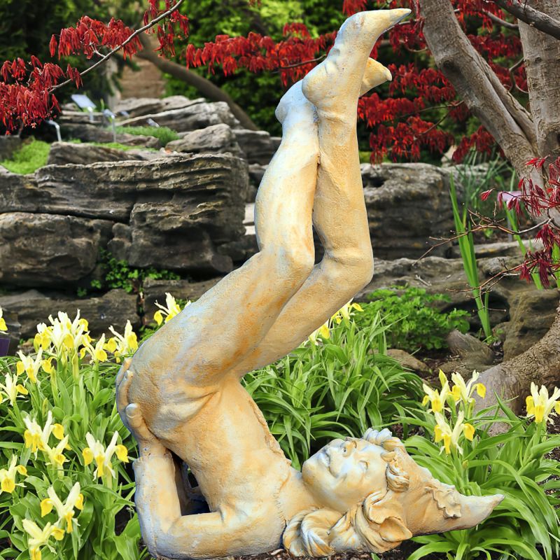 Statue en pierre d'une fille debout sur la tête, entourée de fleurs et d'arbres