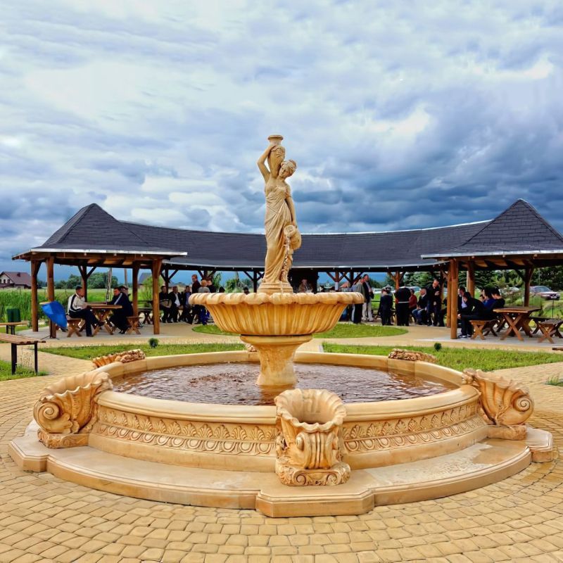 Grande fontana decorativa in pietra con una statua al centro e padiglioni sullo sfondo