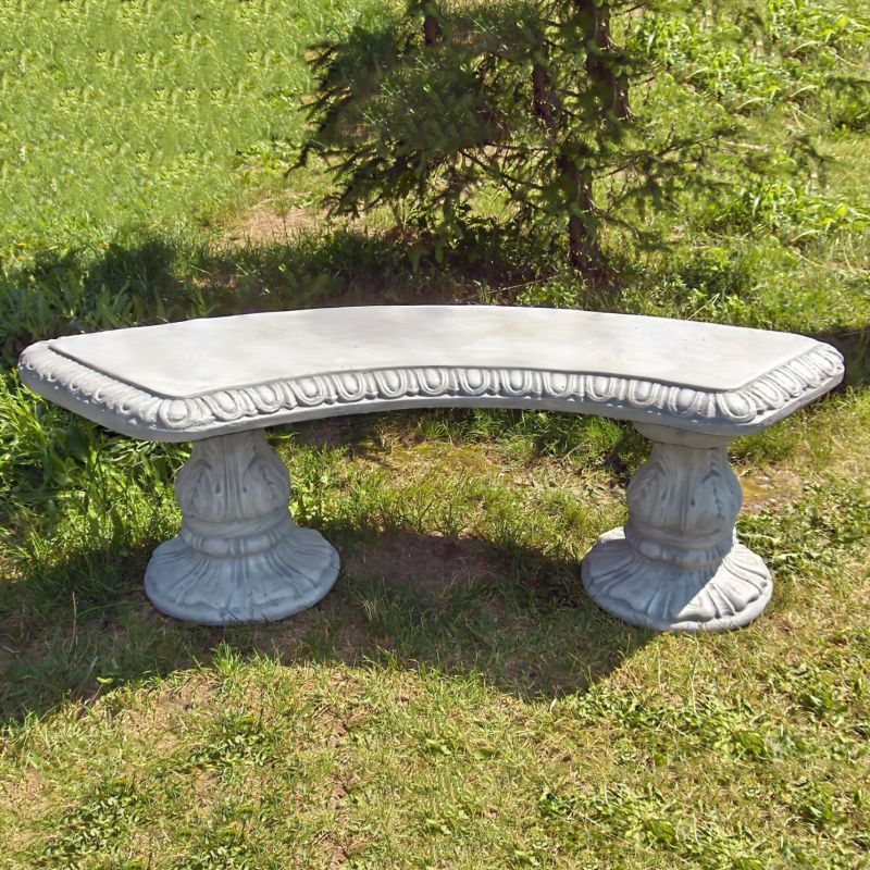 Panchina semicircolare in pietra nel giardino con alberi verdi