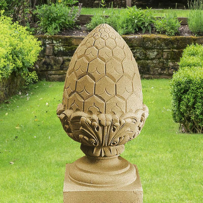 Scultura in pietra arenaria a forma di pigna su colonna nel giardino verde