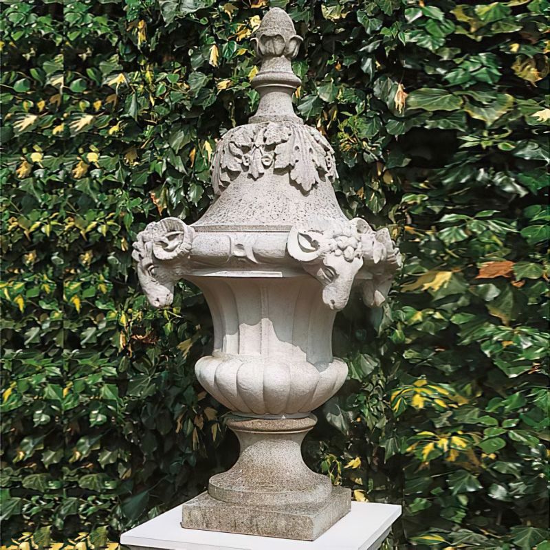 Fontana da giardino in pietra artisticamente scolpita davanti a un muro di edera verde