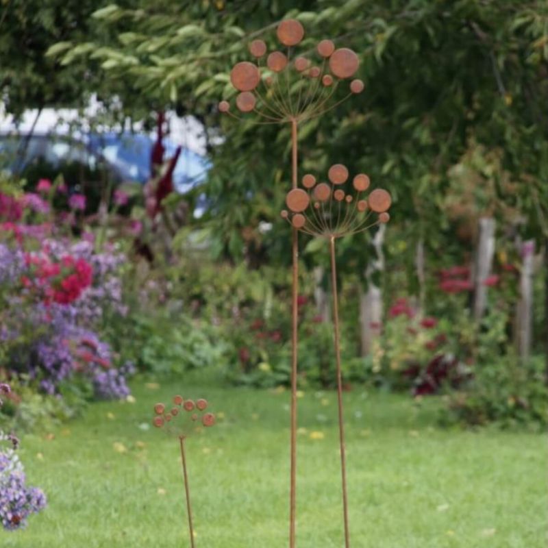 Ornement de jardin décoratif en métal avec plusieurs éléments circulaires dans un jardin verdoyant