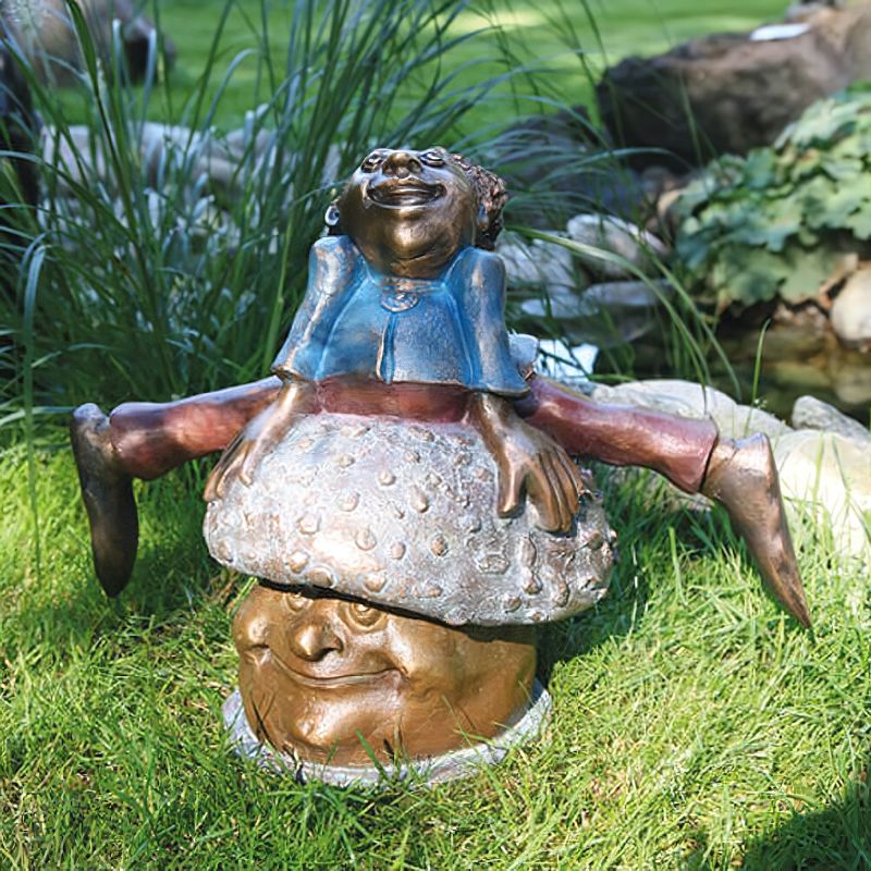 Statue en bronze d'une figure dansante souriante comme décoration de jardin sur l'herbe