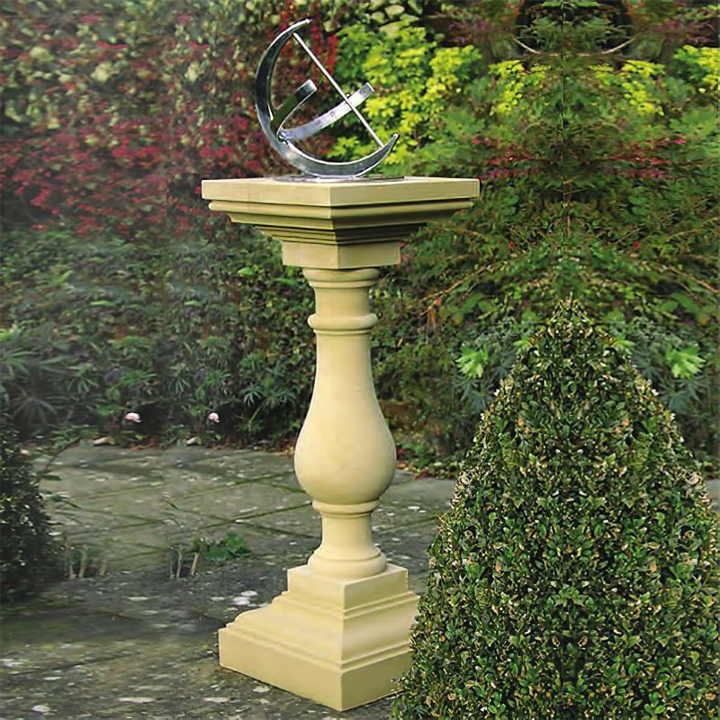 Horloge solaire beige sur un socle en pierre élevé entourée de verdure et de buissons