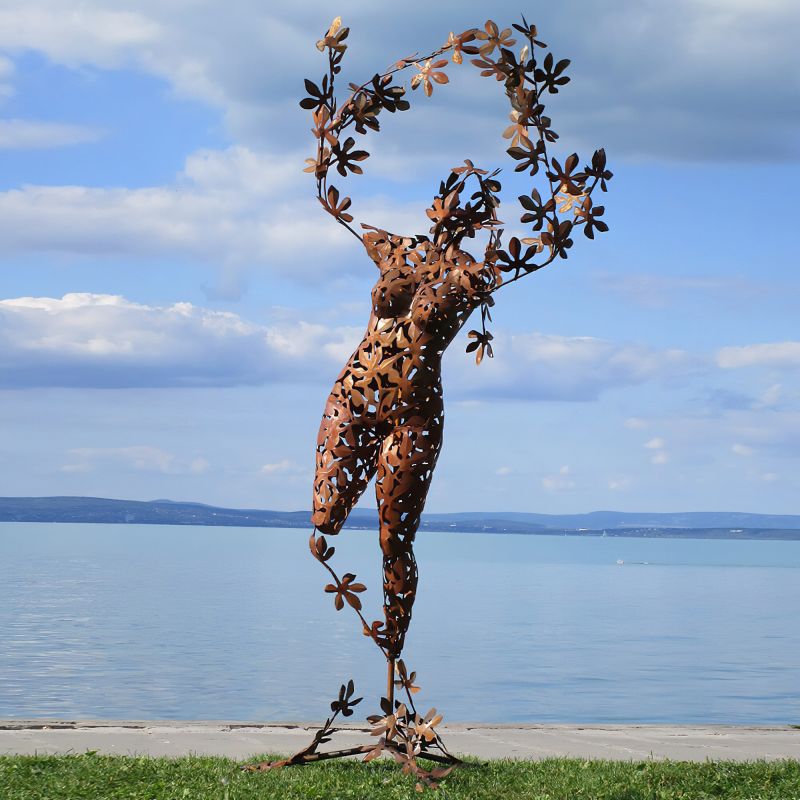 Sculpture en métal d'une figure dansante avec des fleurs, décoration de jardin au bord du lac
