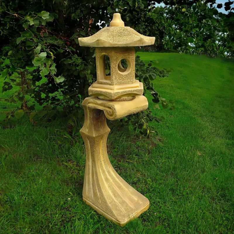 Lanterne en pierre au design asiatique sur pelouse verte dans le jardin