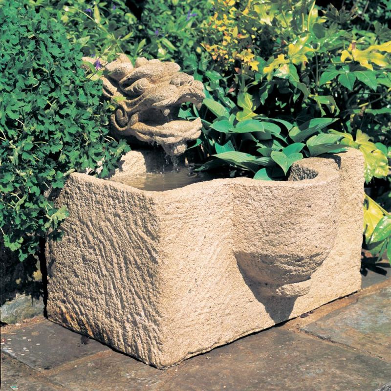 Fontana in pietra con vasca d'acqua, circondata da piante nel giardino