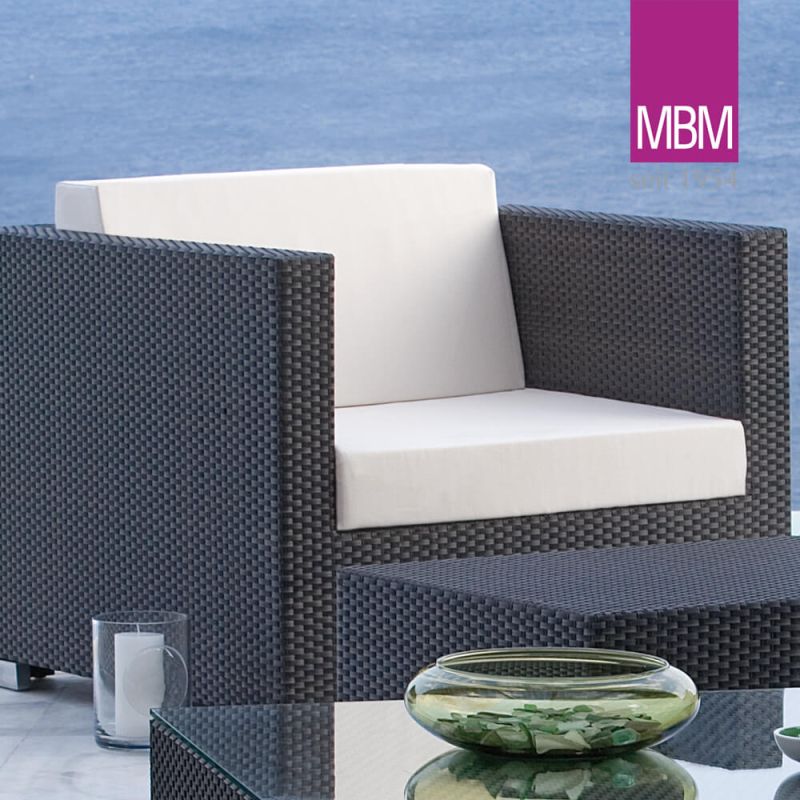 Poltrona da giardino in rattan nero con cuscini bianchi su sfondo blu