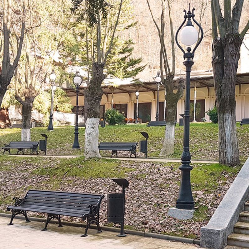 Un parc avec plusieurs bancs de jardin, des arbres et des lanternes décoratives en automne