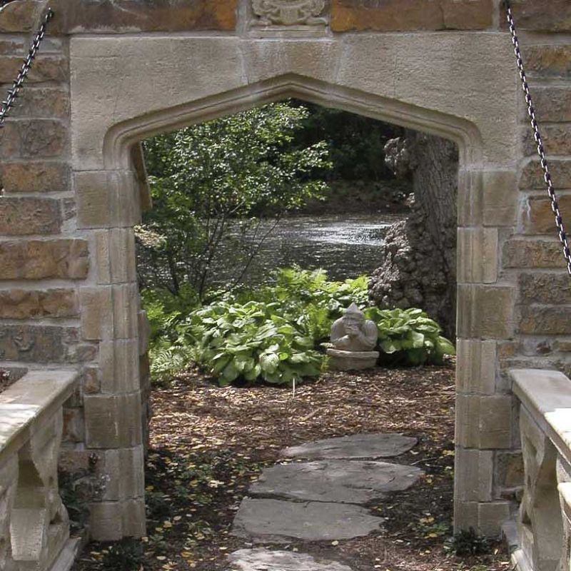 Cornice in pietra che mostra un sentiero del giardino con piante verdi e una scultura