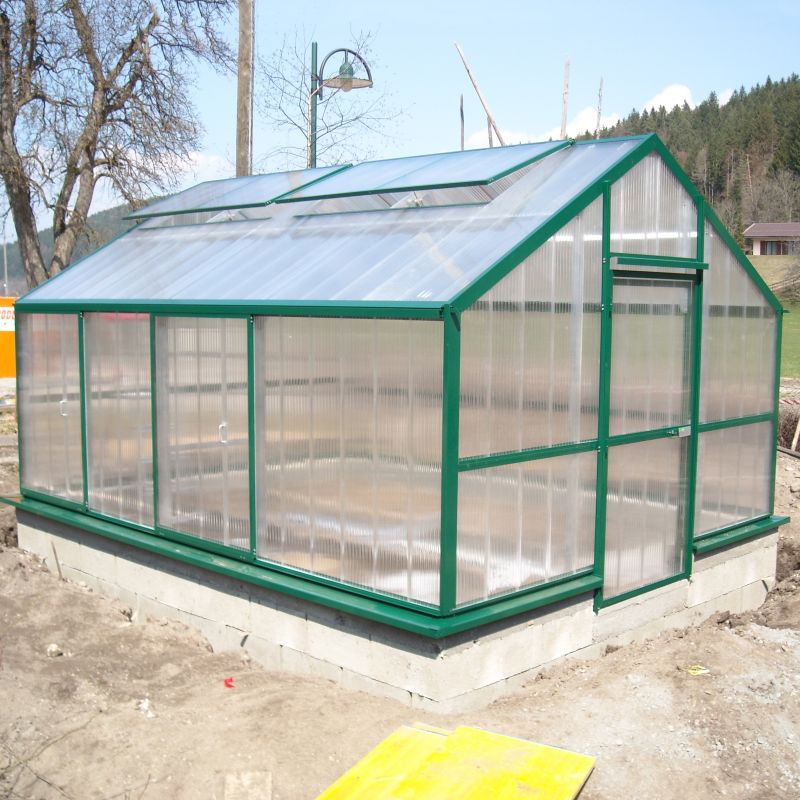 Serre solide avec cadre en métal vert et panneaux transparents en plastique dans un jardin
