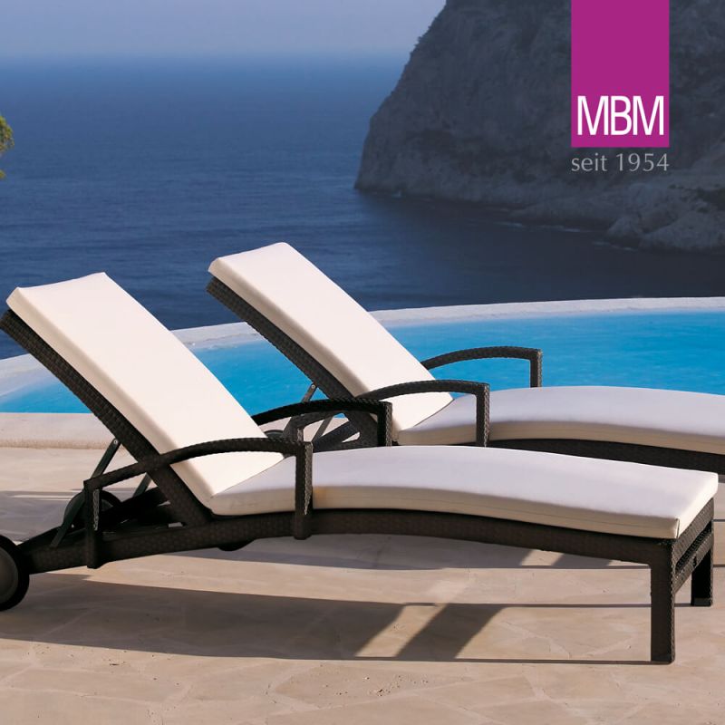 Due lettini da giardino bianchi con struttura nera vicino a una piscina con vista sul mare