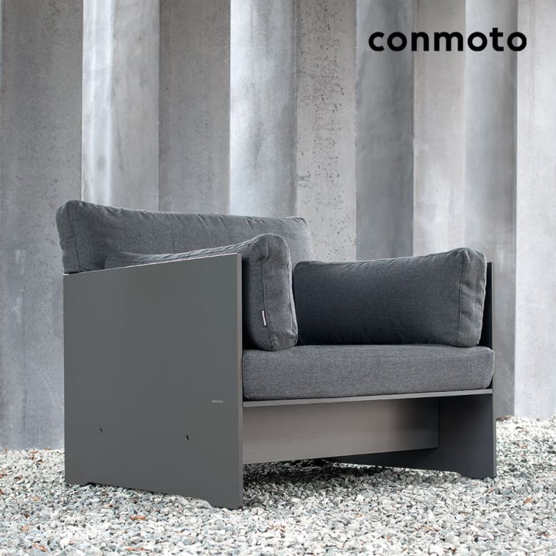 Fauteuil de jardin gris avec coussins devant un mur en béton