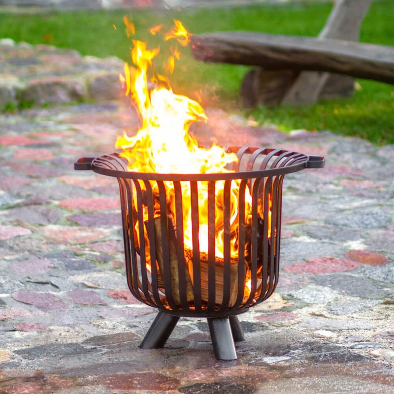 Brasero métallique avec bois en feu sur sol pavé dans un jardin
