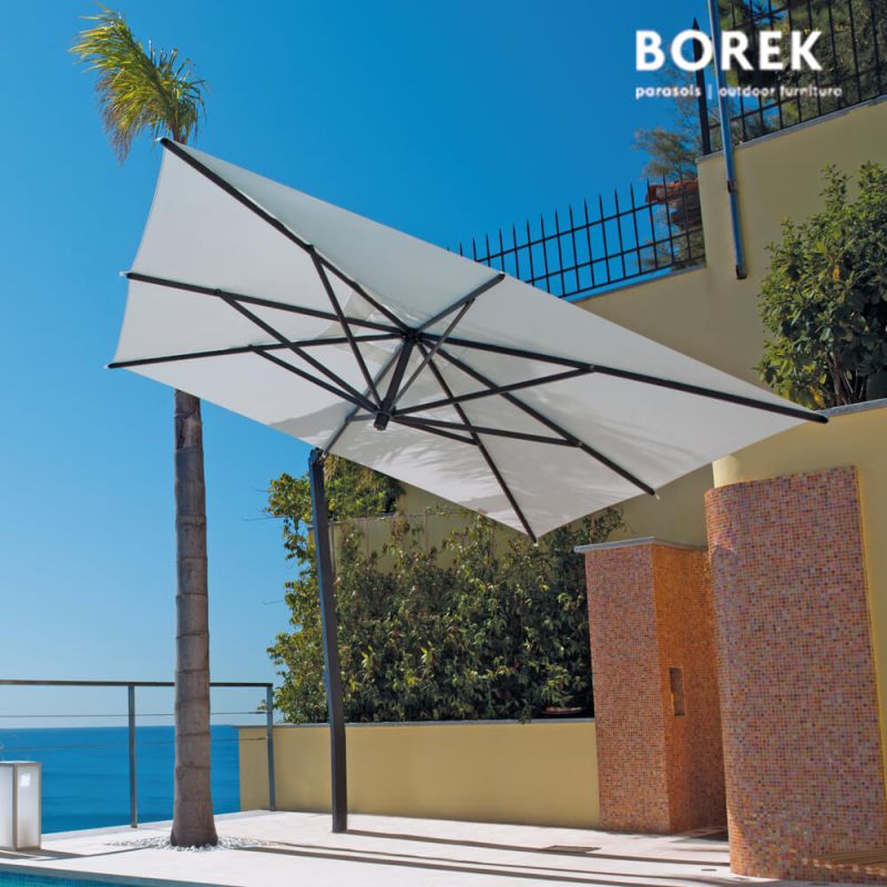 Parasol de jardin blanc avec barre transversale sur terrasse avec vue sur mer et palmiers