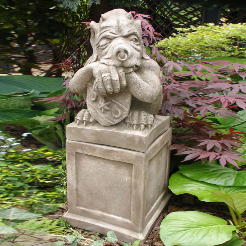 Decorazione per giardino: scultura di un gargoyle su piedistallo tra piante