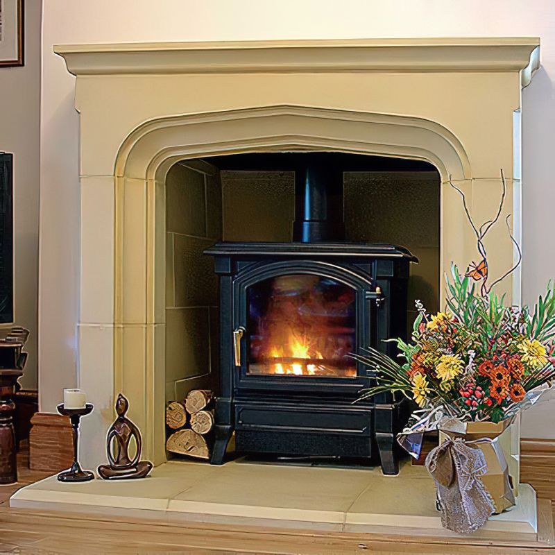 Poêle à bois en feu dans un salon avec un arrangement floral et des bougies