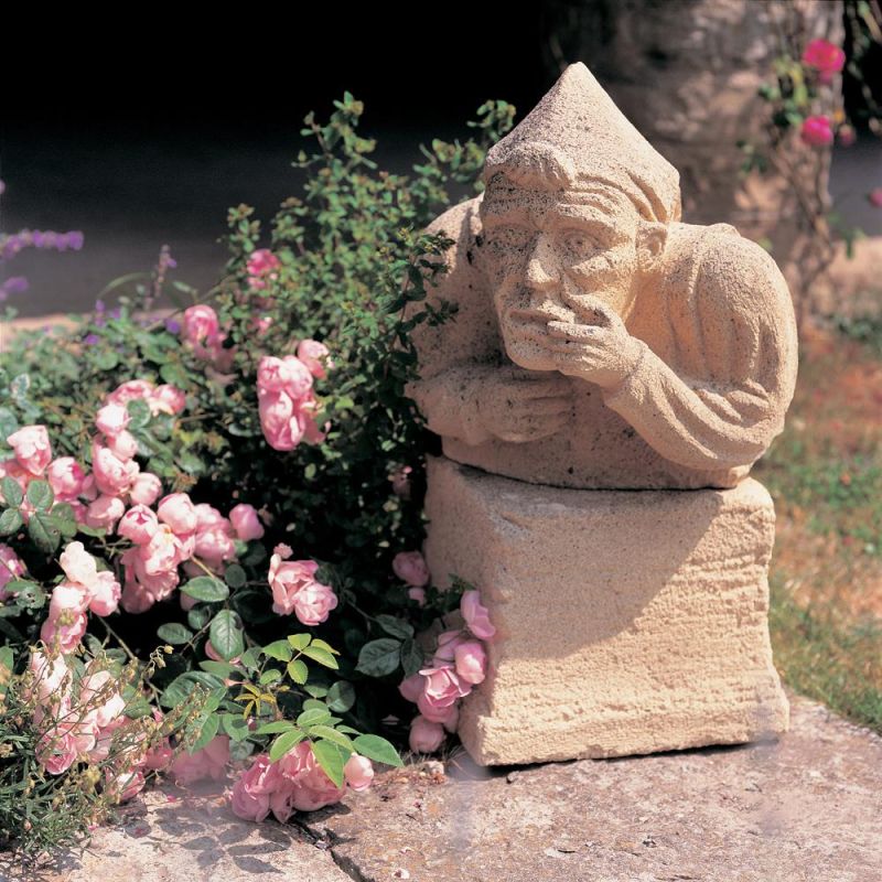 Sculpture en pierre d'un homme pensif à côté de roses roses dans le jardin