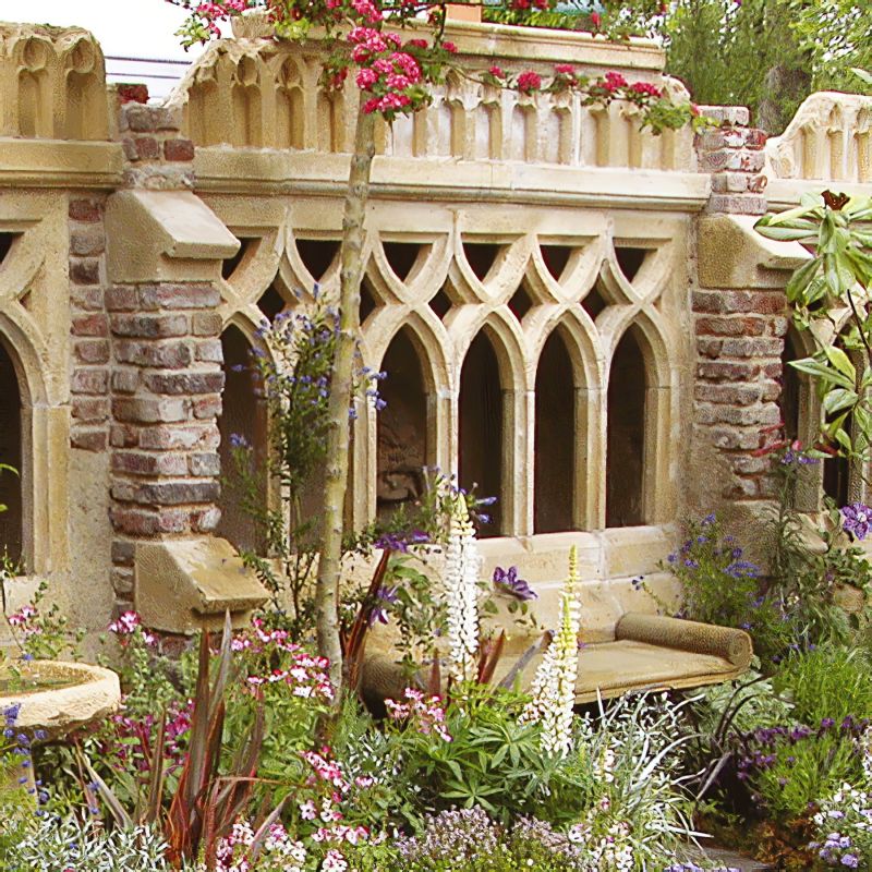 Banc en pierre ancien dans un jardin avec des plantes fleuries et un mur en pierre décoratif