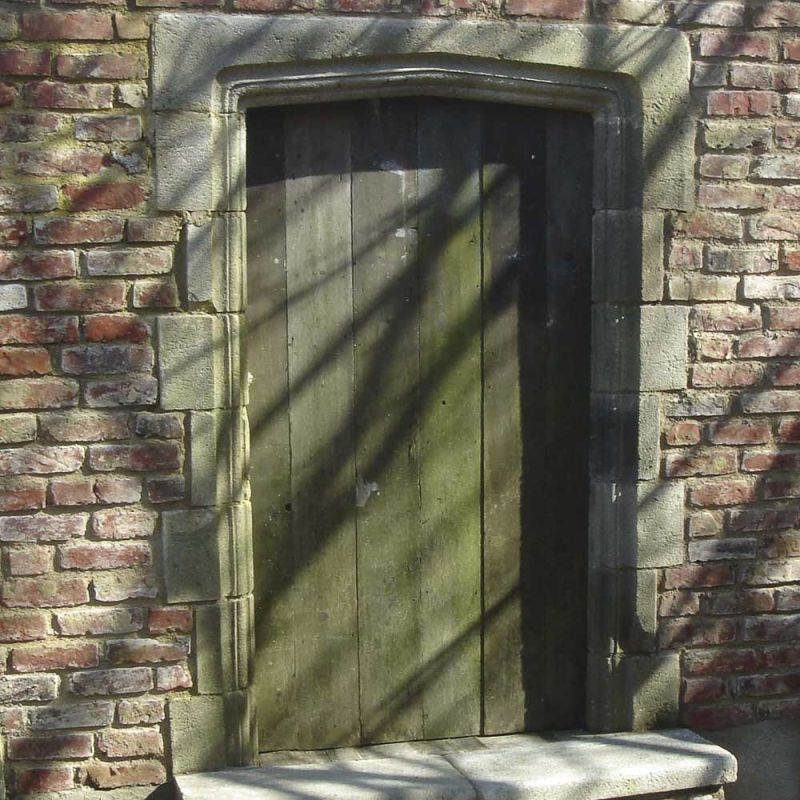 Ancienne porte en bois verte dans un mur de pierre rustique avec ombres, décoration de jardin