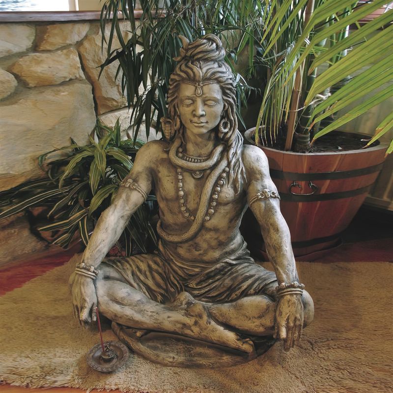 Statue de méditation de couleur bronze assise dans le jardin entourée de plantes et de pots de fleurs