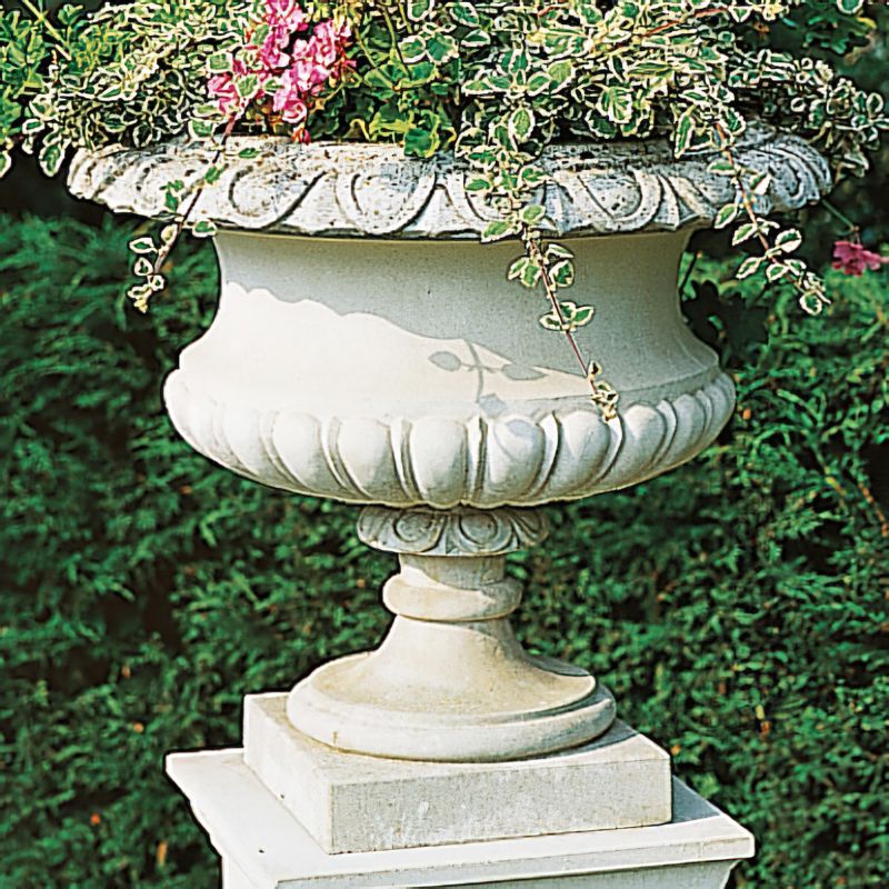 Jardinière en pierre blanche avec plantes vertes et fleurs dans le jardin