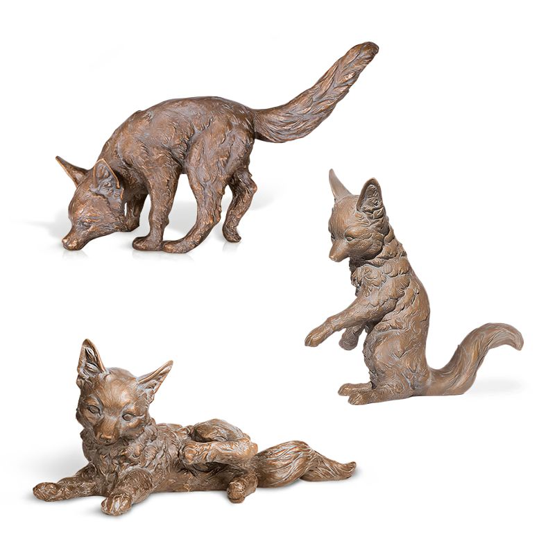 Trois sculptures de renards bruns dans différentes poses comme décoration de jardin