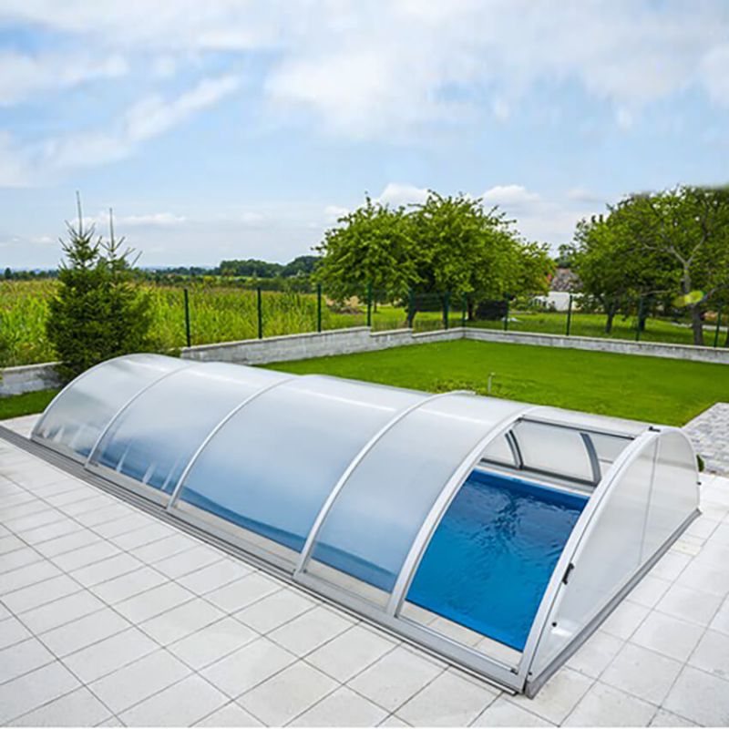 Piscine moderne avec couverture transparente sur une terrasse pavée dans le jardin