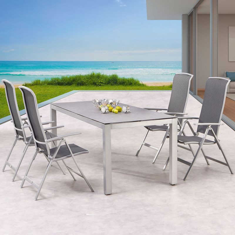 Elegante tavolo da giardino con sei sedie grigie su terrazza con vista sul mare