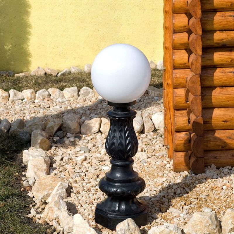 Lampe sphérique blanche sur socle noir décoratif dans le jardin près d'une maison en bois